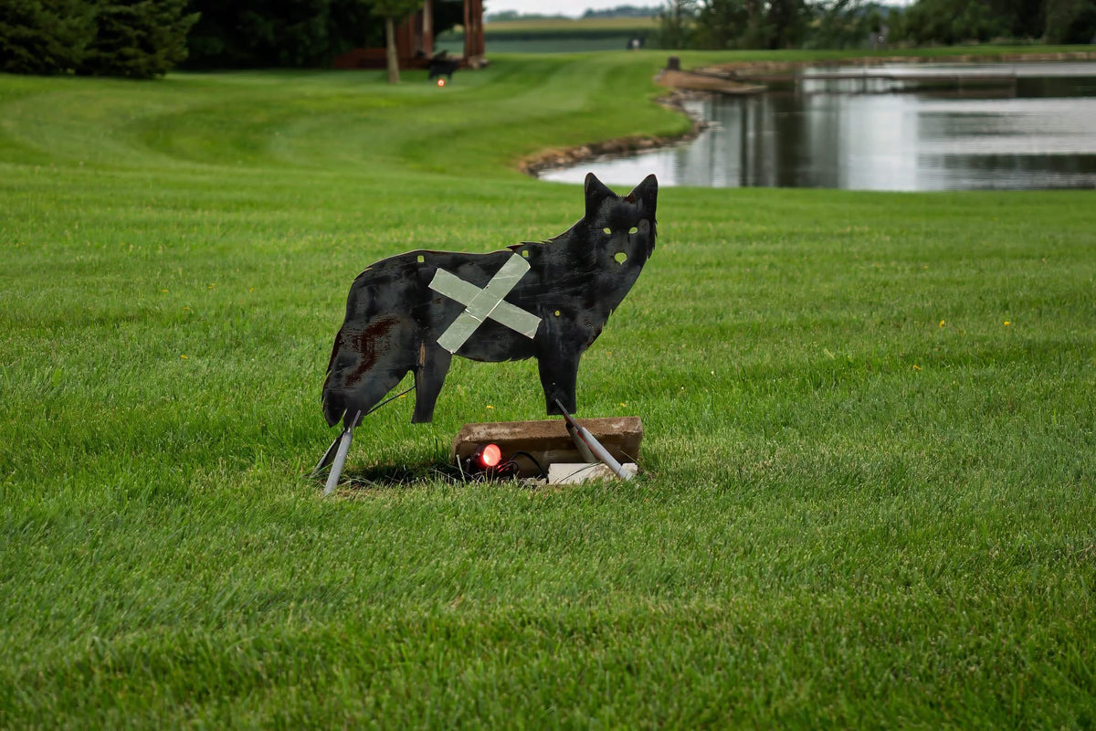 Life-size SR500 Coyote Steel Target features a side profile with reactive vital zones, set on a grassy field by Atlas Targets